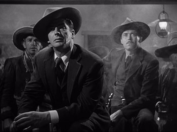 Movie still from “My Darling Clementine” (1946), directed by John Ford – A group of men sitting next to each other wearing hats; Medium shot, Low angle