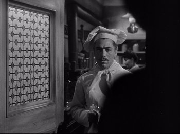 Movie still from “My Darling Clementine” (1946), directed by John Ford – A black and white photo of a man wearing a chef's hat; Medium shot, Over the shoulder angle
