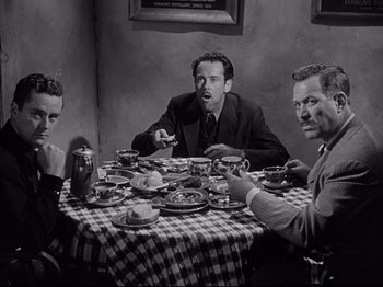 Movie still from “My Darling Clementine” (1946), directed by John Ford – A group of men sitting around a table eating food; Medium shot, High angle