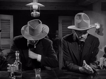 Movie still from “My Darling Clementine” (1946), directed by John Ford – A couple of men sitting at a table; Medium shot, Low angle