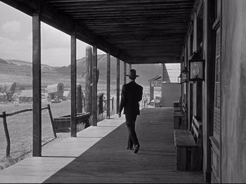 Movie still from “My Darling Clementine” (1946), directed by John Ford – A man walking down a street with a hat on; Wide shot, Low angle