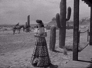 Movie still from “My Darling Clementine” (1946), directed by John Ford – A black and white photo of a woman standing in front of cacti; Wide shot, Over the shoulder angle