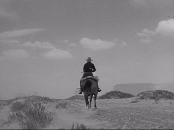 Movie still from “My Darling Clementine” (1946), directed by John Ford – A man riding on the back of a horse in the desert; Extreme Wide shot, Low angle