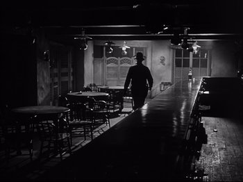 Movie still from “My Darling Clementine” (1946), directed by John Ford – A man walking down the aisle of an old fashioned restaurant; Wide shot, Low angle