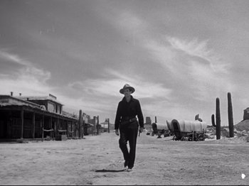 Movie still from “My Darling Clementine” (1946), directed by John Ford – An old photo of a man in a cowboy hat walking in the desert; Wide shot, Low angle