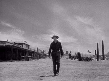 Movie still from “My Darling Clementine” (1946), directed by John Ford – A man wearing a hat and a cowboy outfit walking in the middle of an open field; Wide shot, Low angle