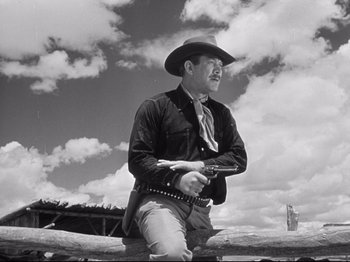 Movie still from “My Darling Clementine” (1946), directed by John Ford – A man holding a gun while wearing a cowboy hat; Medium shot, Low angle