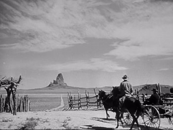Movie still from “My Darling Clementine” (1946), directed by John Ford – A man riding a horse and carriage down a dirt road; Extreme Wide shot, Low angle