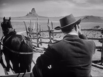 Movie still from “My Darling Clementine” (1946), directed by John Ford – A man riding a horse drawn carriage across a desert landscape; Wide shot, Low angle