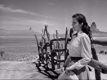 Movie still from “My Darling Clementine” (1946), directed by John Ford – A woman standing next to a fence on a beach; Medium shot, Low angle