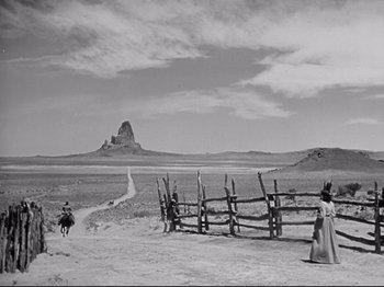 Movie still from “My Darling Clementine” (1946), directed by John Ford – A black and white photo of a man and a woman near a wooden fence; Extreme Wide shot, Low angle