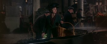 Movie still from “My Fair Lady” (1964), directed by George Cukor – A woman in a hat and a green jacket holding a basket; Medium shot, Low angle