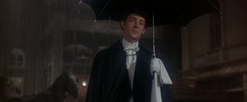 Movie still from “My Fair Lady” (1964), directed by George Cukor – A man holding an umbrella while standing in the rain; Close Up shot, Low angle