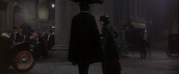 Movie still from “My Fair Lady” (1964), directed by George Cukor – A man and a woman standing next to each other holding an umbrella; Wide shot, Low angle