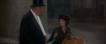Movie still from “My Fair Lady” (1964), directed by George Cukor – A man and a woman wearing hats and holding flowers; Medium shot, Over the shoulder angle