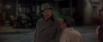 Movie still from “My Fair Lady” (1964), directed by George Cukor – A man wearing a hat and a coat standing next to another man wearing a hat; Medium shot, Over the shoulder angle