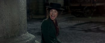Movie still from “My Fair Lady” (1964), directed by George Cukor – A woman wearing a black hat and a green jacket; Medium shot, Low angle
