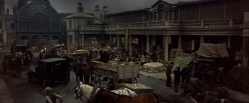 Movie still from “My Fair Lady” (1964), directed by George Cukor – An old time scene with a horse drawn carriage and people; Extreme Wide shot, High angle