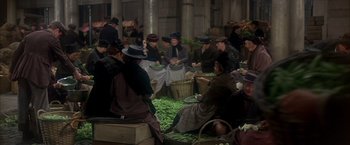 Movie still from “My Fair Lady” (1964), directed by George Cukor – A group of people sitting around a table with green beans on it; Wide shot, High angle