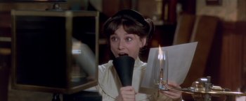 Movie still from “My Fair Lady” (1964), directed by George Cukor – A woman holding a blow dryer up to her mouth; Medium shot, High angle