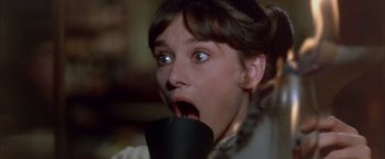 Movie still from “My Fair Lady” (1964), directed by George Cukor – A woman with a surprised look on her face holding a cup; Close Up shot, High angle