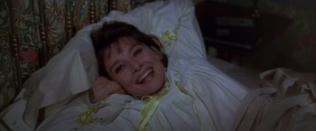 Movie still from “My Fair Lady” (1964), directed by George Cukor – A woman laying in a bed smiling for the camera; Close Up shot, Overhead angle