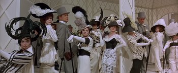 Movie still from “My Fair Lady” (1964), directed by George Cukor – A group of people in fancy hats and dresses; Medium shot, Low angle