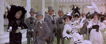 Movie still from “My Fair Lady” (1964), directed by George Cukor – A group of men and women wearing hats and holding binoculars; Medium shot, Low angle