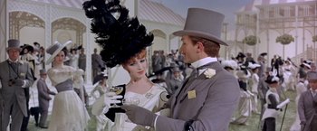 Movie still from “My Fair Lady” (1964), directed by George Cukor – A man and a woman in formal wear at an outdoor event; Medium shot, Low angle