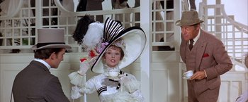 Movie still from “My Fair Lady” (1964), directed by George Cukor – A woman in a white dress holding a cup in her hand; Medium shot, Low angle