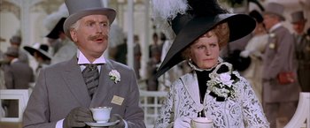 Movie still from “My Fair Lady” (1964), directed by George Cukor – A man and a woman wearing fancy hats and holding cups; Close Up shot, Low angle