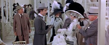 Movie still from “My Fair Lady” (1964), directed by George Cukor – A man and a woman in fancy hats and costumes; Medium shot, Over the shoulder angle