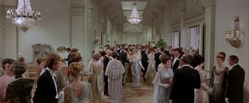 Movie still from “My Fair Lady” (1964), directed by George Cukor – A group of people in formal wear standing in a room; Wide shot, High angle