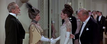 Movie still from “My Fair Lady” (1964), directed by George Cukor – Two women dressed in formal wear shaking hands; Medium shot, Over the shoulder angle