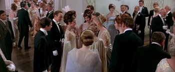 Movie still from “My Fair Lady” (1964), directed by George Cukor – A group of people standing around each other in formal wear; Medium shot, High angle