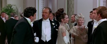 Movie still from “My Fair Lady” (1964), directed by George Cukor – A group of people standing next to each other in formal wear; Medium shot, Over the shoulder angle