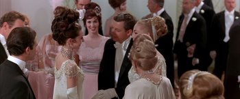 Movie still from “My Fair Lady” (1964), directed by George Cukor – A group of people in formal wear talking to each other; Medium shot, Over the shoulder angle