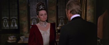 Movie still from “My Fair Lady” (1964), directed by George Cukor – A woman wearing a tiara and a red jacket; Medium shot, Over the shoulder angle