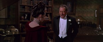 Movie still from “My Fair Lady” (1964), directed by George Cukor – A man in a tuxedo and a woman in a red dress; Medium shot, Over the shoulder angle