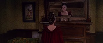 Movie still from “My Fair Lady” (1964), directed by George Cukor – A woman in a red dress looking in a mirror; Medium shot, Over the shoulder angle