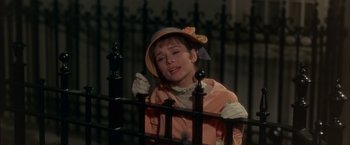 Movie still from “My Fair Lady” (1964), directed by George Cukor – A young girl wearing a hat and gloves is leaning on a fence; Close Up shot, Low angle
