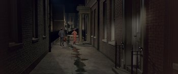 Movie still from “My Fair Lady” (1964), directed by George Cukor – Two people walking down a sidewalk at night; Extreme Wide shot, High angle