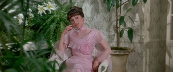 Movie still from “My Fair Lady” (1964), directed by George Cukor – A woman in a pink dress sitting in a chair; Medium shot, Low angle