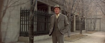 Movie still from “My Fair Lady” (1964), directed by George Cukor – A man in a suit and hat standing on the sidewalk; Medium shot, Low angle