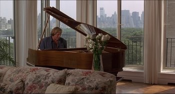 Movie still from “My Father the Hero” (1994), directed by Steve Miner – A man sitting in front of a grand piano in a living room; Wide shot, Low angle