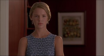 Movie still from “My Father the Hero” (1994), directed by Steve Miner – A woman in a blue dress is standing in front of a painting; Close Up shot, Over the shoulder angle