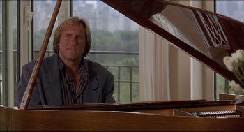 Movie still from “My Father the Hero” (1994), directed by Steve Miner – A man sitting at a piano in front of a window; Medium shot, Low angle