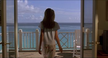 Movie still from “My Father the Hero” (1994), directed by Steve Miner – A woman standing on a porch looking out at the ocean; Wide shot, Over the shoulder angle