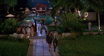 Movie still from “My Father the Hero” (1994), directed by Steve Miner – A group of people walking down a sidewalk near a swimming pool; Extreme Wide shot, High angle