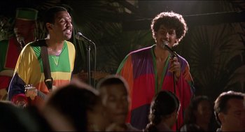 Movie still from “My Father the Hero” (1994), directed by Steve Miner – Two men sing into microphones in front of an audience; Medium shot, Low angle